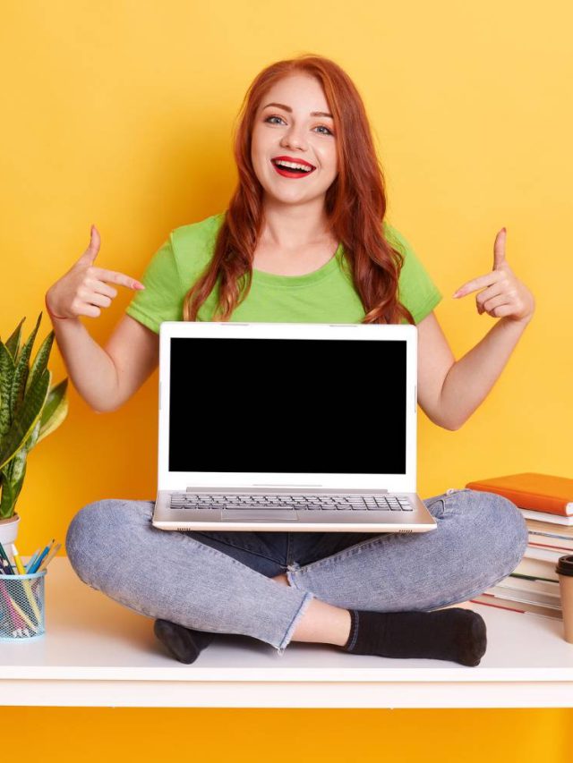 astonished-excited-female-with-lap-top-knees-showing-blank-screen-pointing-it-with-index-fingers_11zon